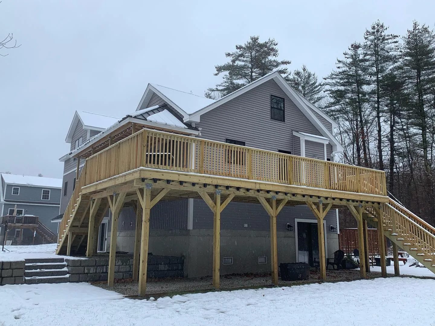 House with wooden deck in snowy yard.