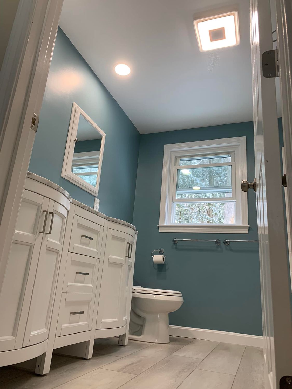 Modern bathroom with blue walls and white vanity.