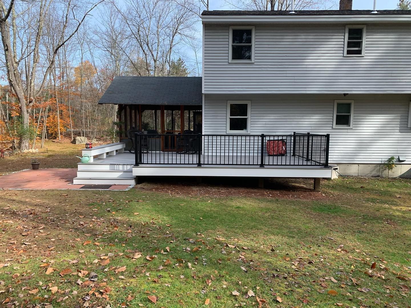 A white two-story house with a black railing porch and steps.