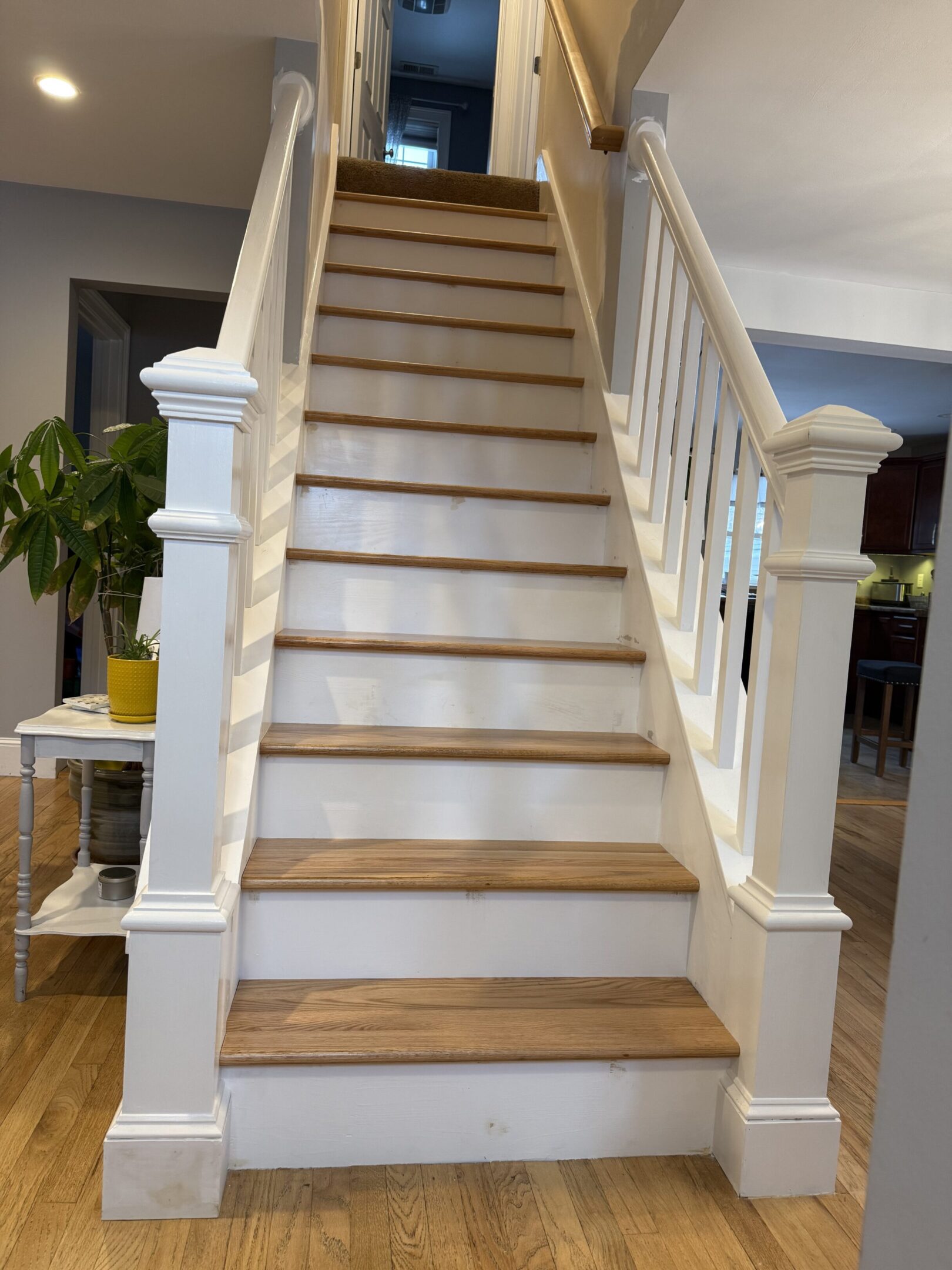 Wooden staircase with white railings in a bright home interior.