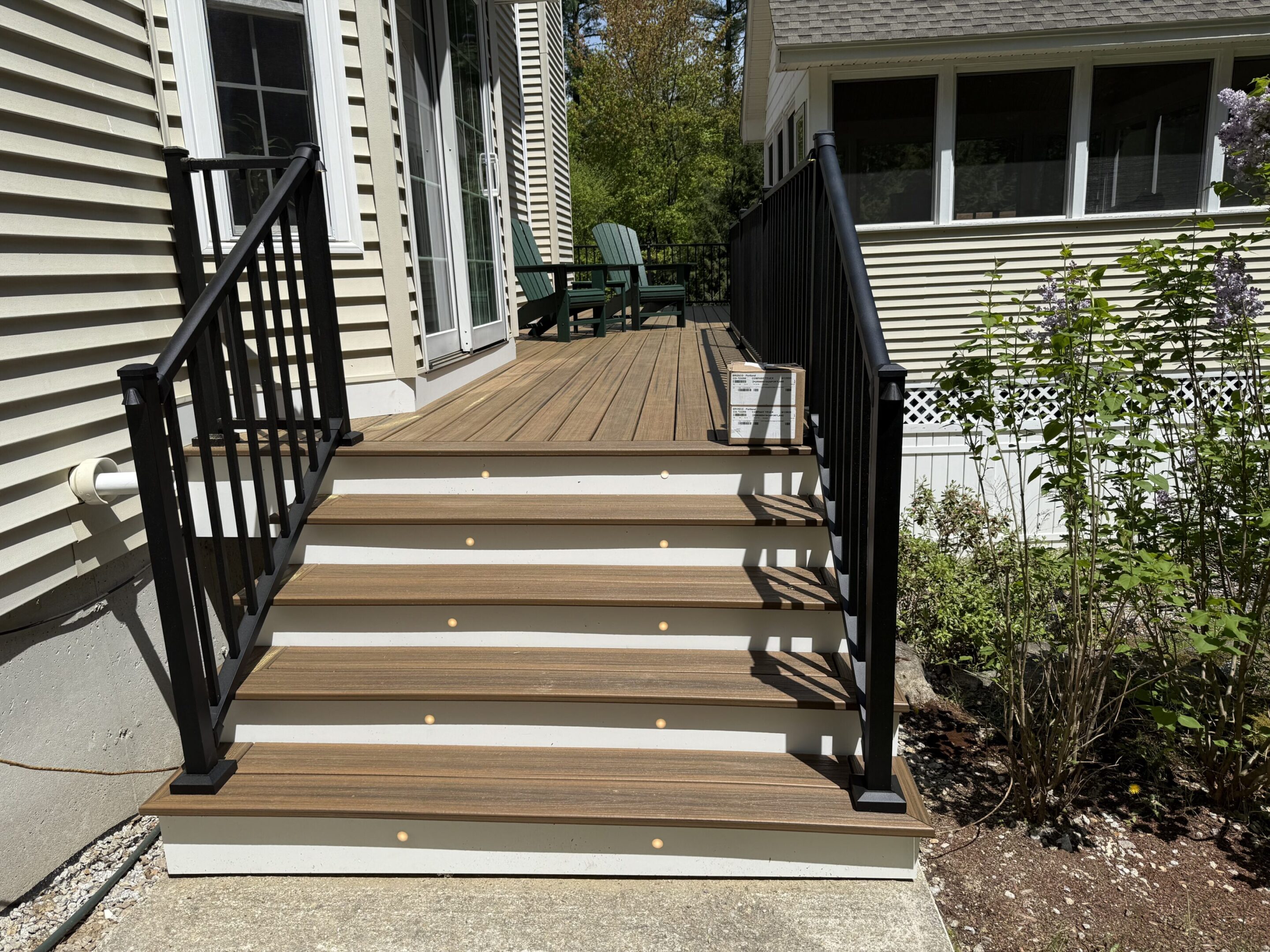 Modern wooden deck with stairs and black metal railings.