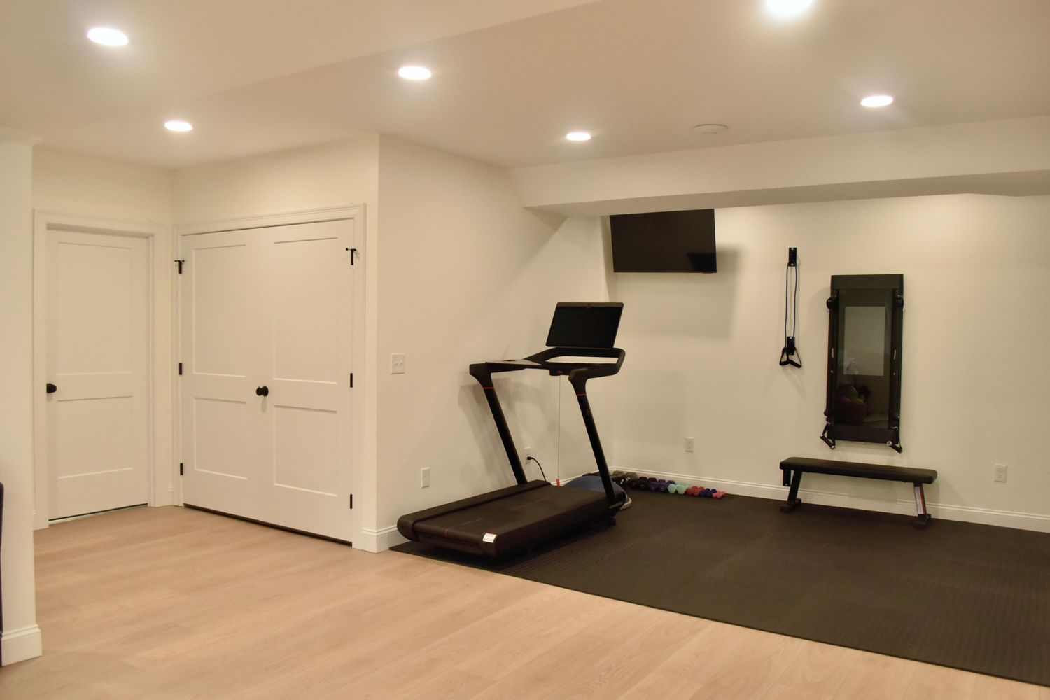 A clean home gym with a treadmill and TV mounted on the wall.