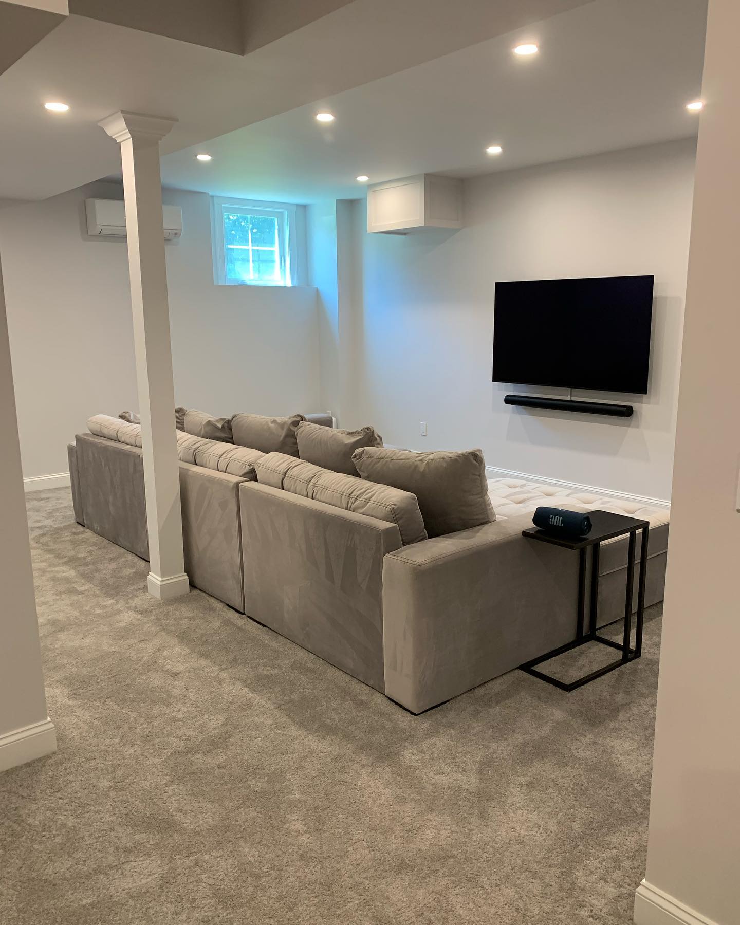 Cozy basement living room with sectional sofa and wall-mounted TV.