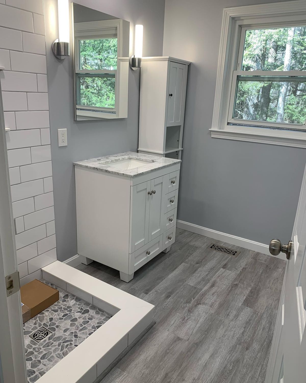 Newly renovated bathroom with modern gray flooring and white vanity.