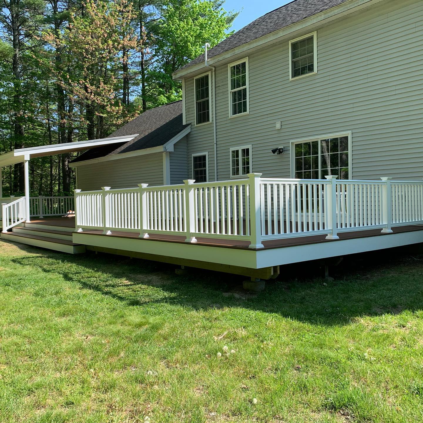 A spacious backyard deck with white railing attached to a house.