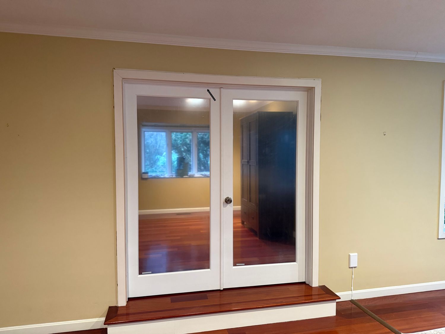 New glass double doors installed with wooden frames in a cozy room.