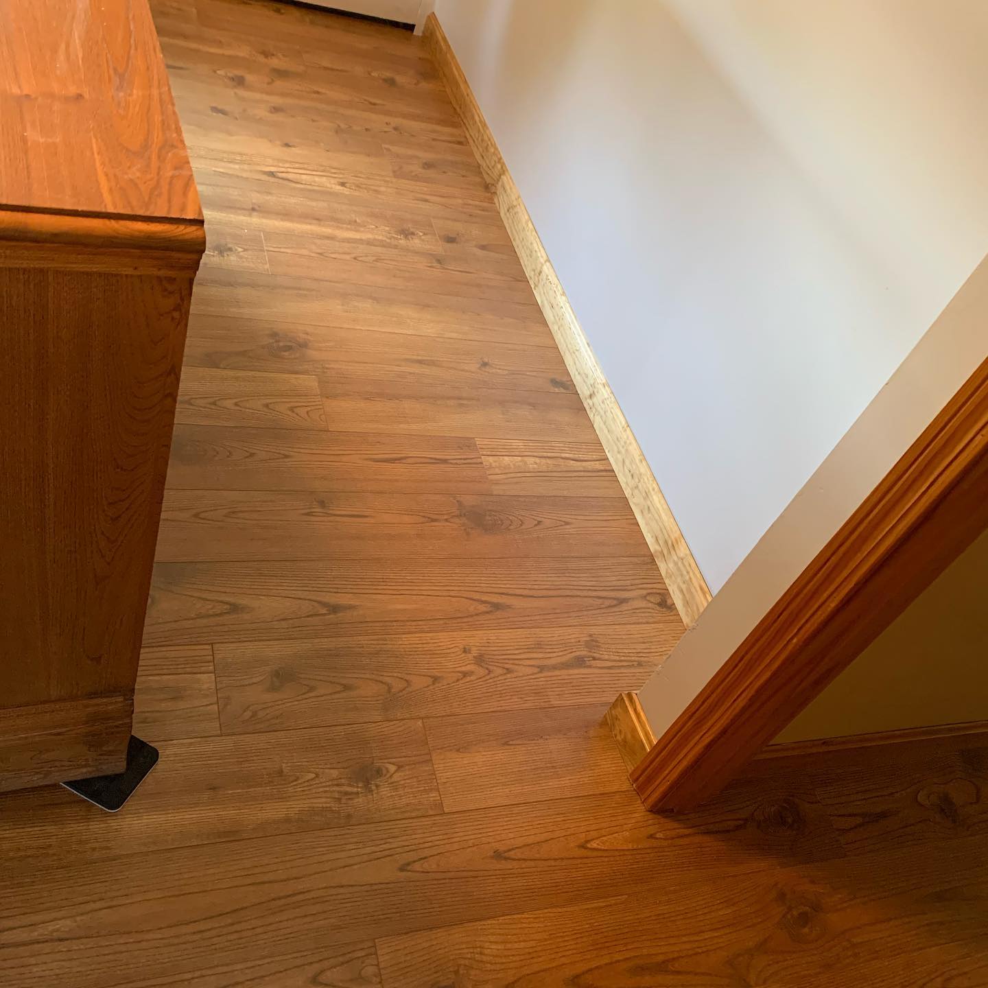 Wooden floor with a small cabinet in a hallway corner.