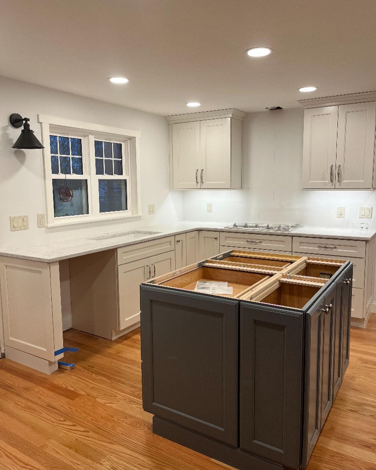 Modern kitchen with white cabinets and a dark island under construction.