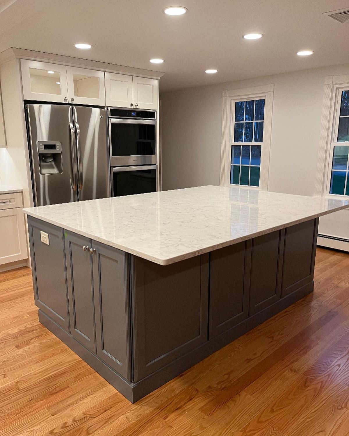 Modern kitchen island with marble countertop and gray cabinetry.