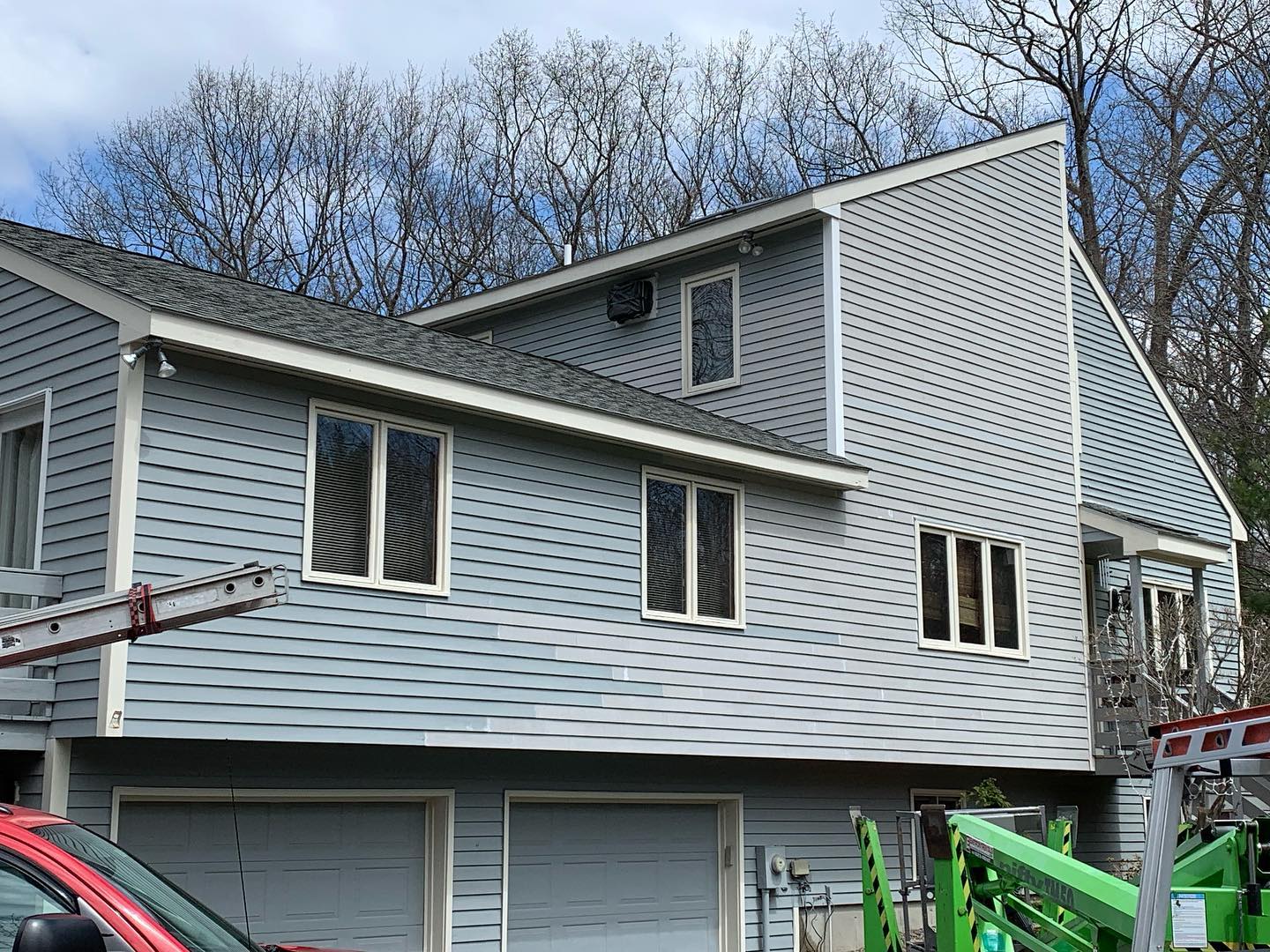 A multi-level house with gray siding and several windows under a clear sky.