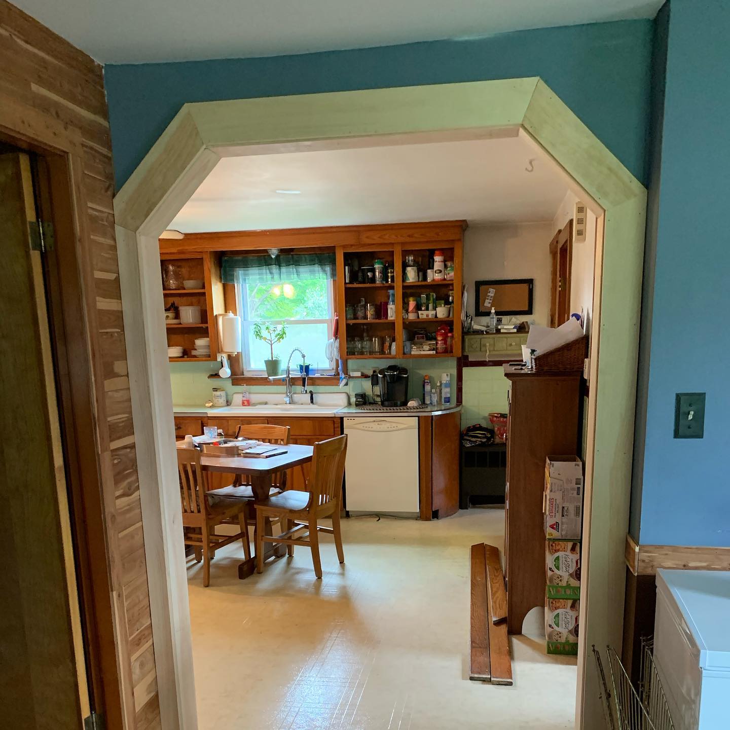 Cozy kitchen and dining area viewed through an archway with wooden trim.