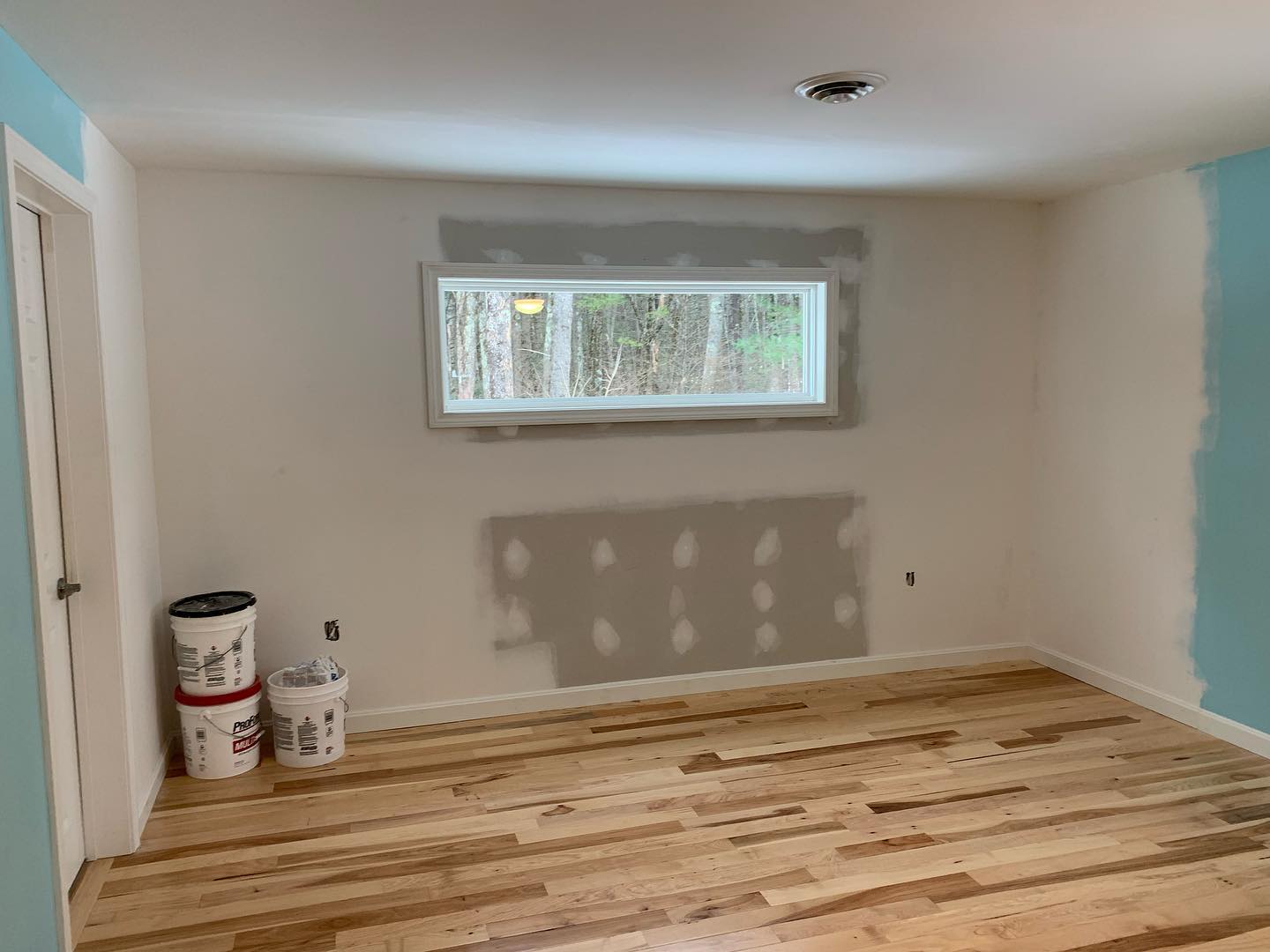 Room with newly installed hardwood floor and painted wall.