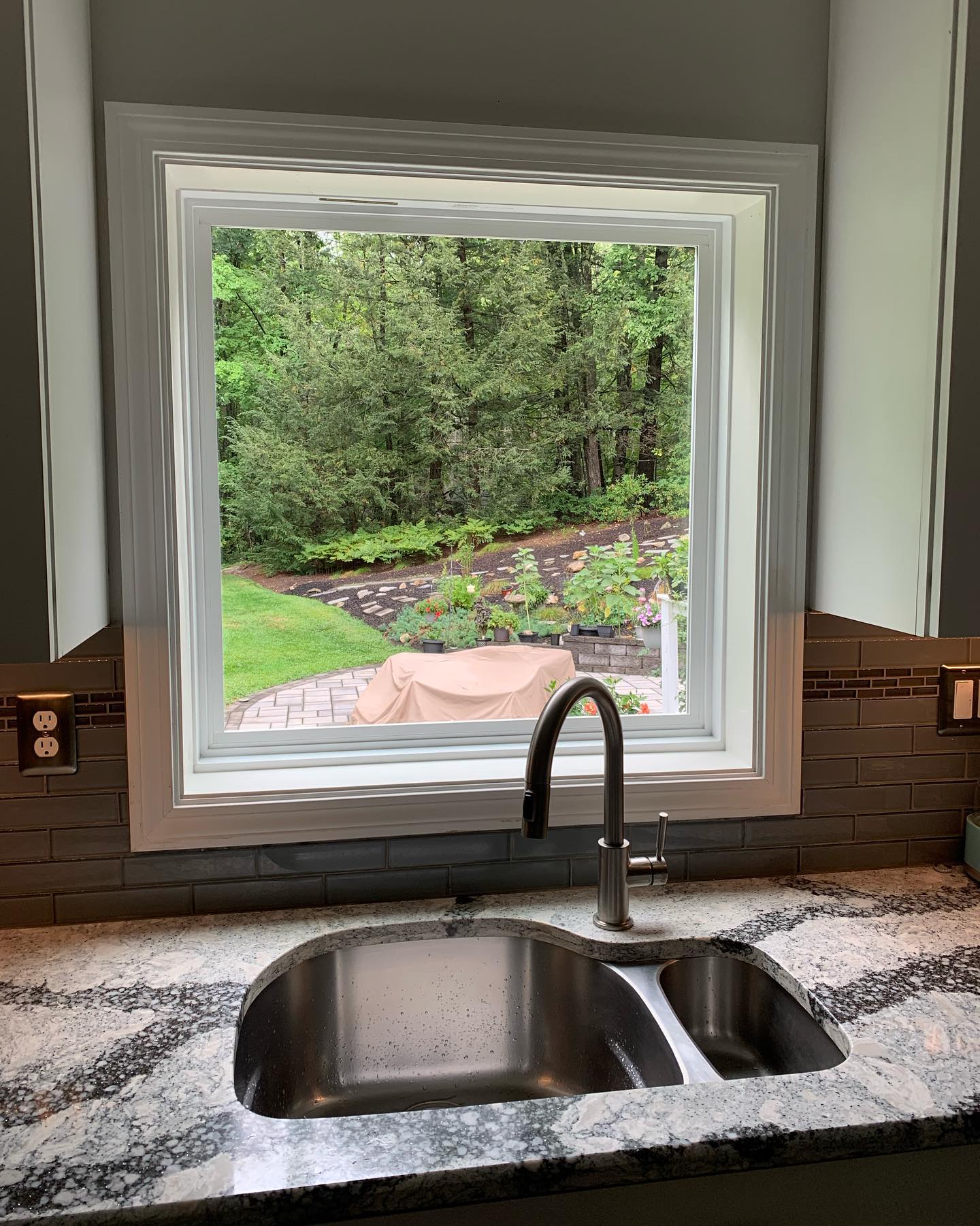 Kitchen sink with a window view of a lush green garden.