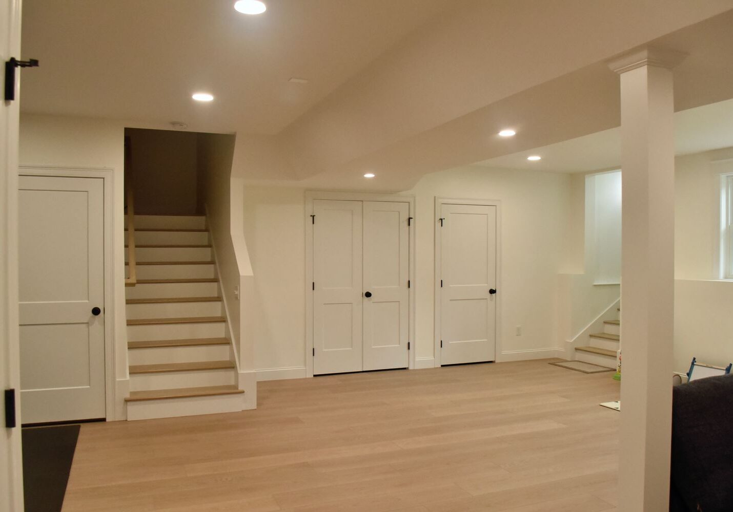 Modern basement with stairs and white doors.
