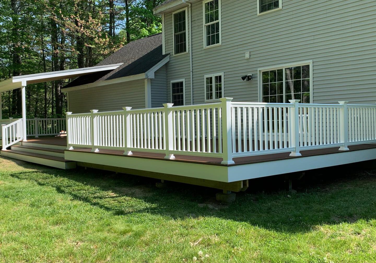 A spacious backyard deck with white railing attached to a house.