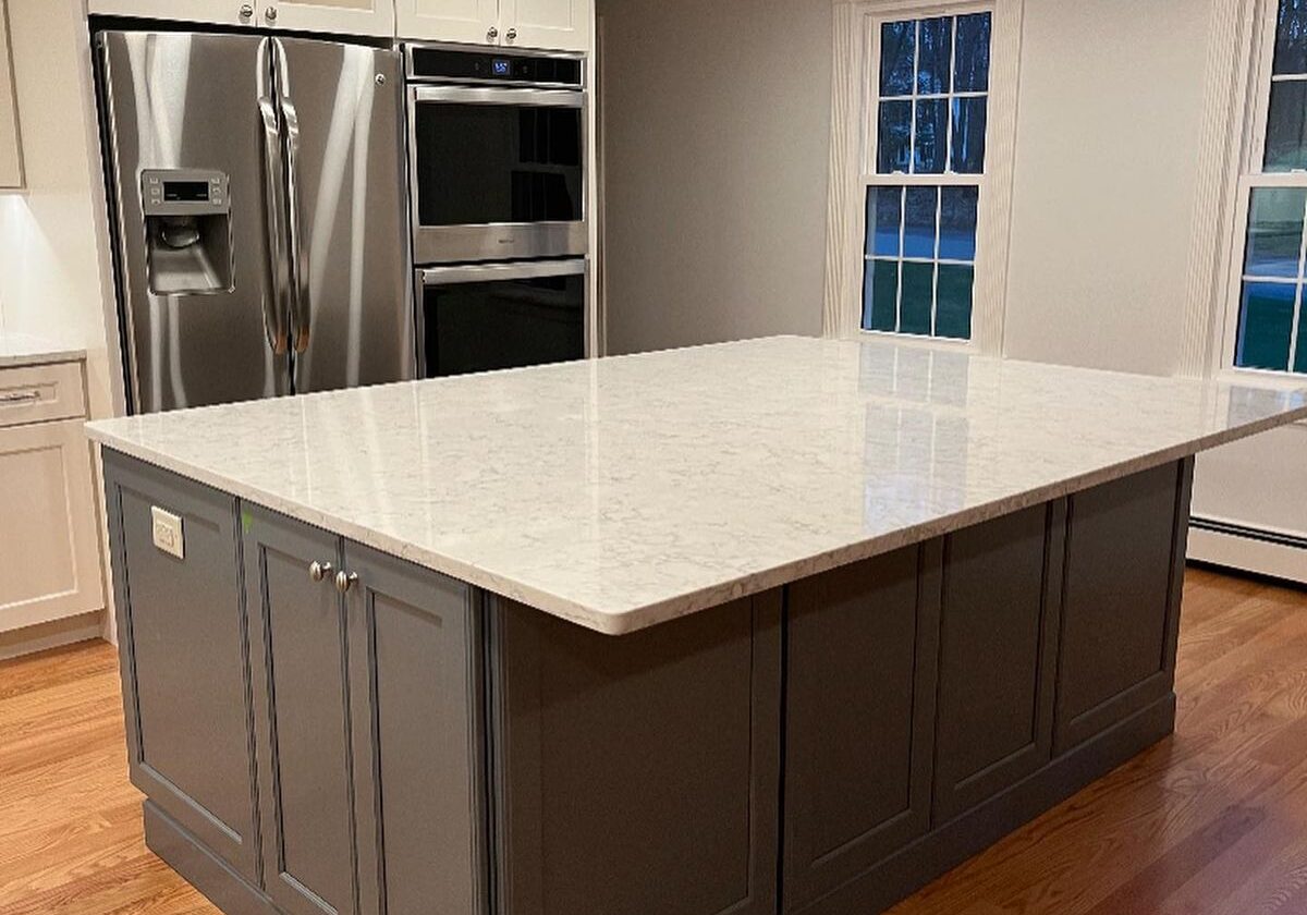 Modern kitchen island with marble countertop and gray cabinetry.