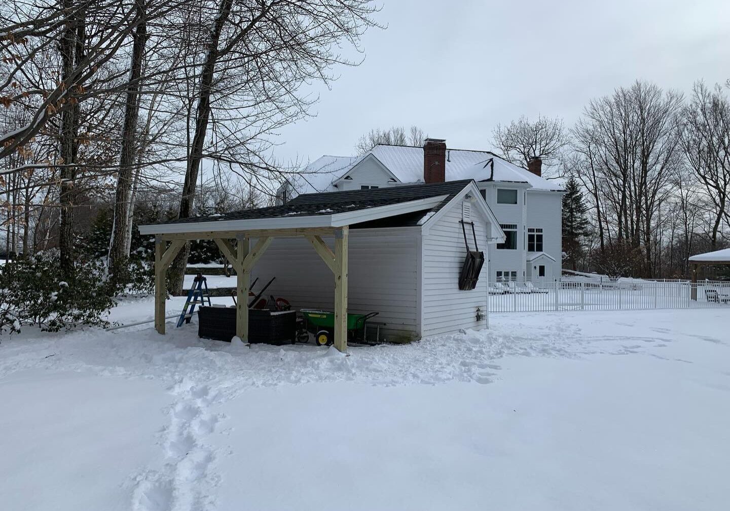 Snow-covered house with a carport and footprints in the snow.